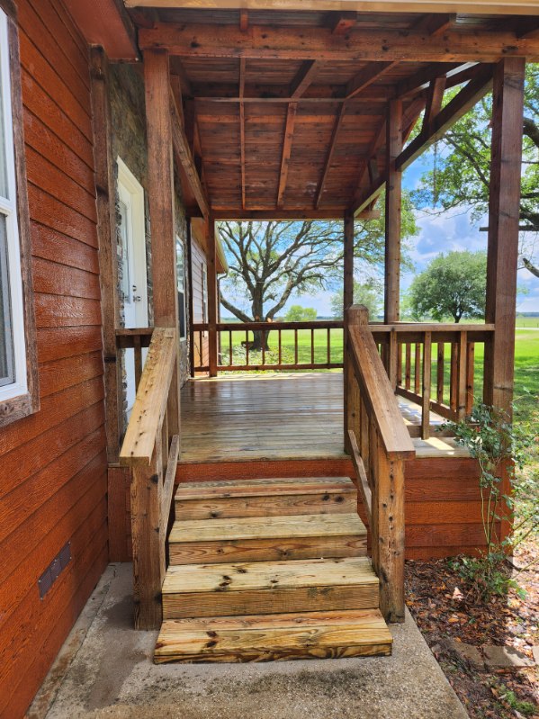 The image shows the porch after house washing services, with freshly cleaned wooden steps and restored railings, appearing much brighter and cleaner.