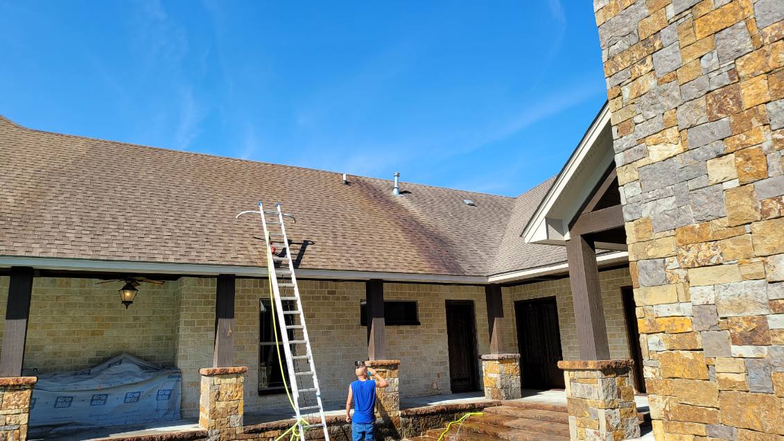 A technician preparing to clean a stained roof on a residential home—an ideal example for promoting professional roof washing services to restore curb appeal and remove buildup.