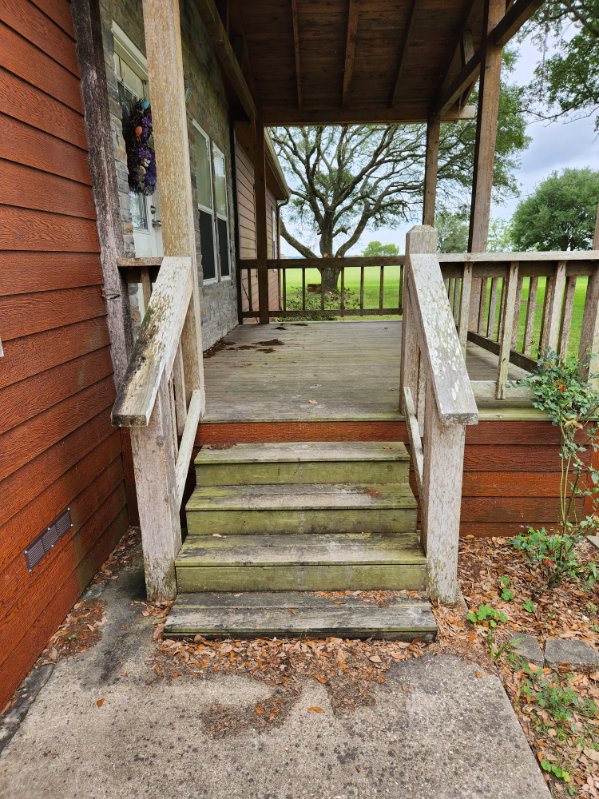 The image shows the porch before house washing services, with weathered, dirty wooden steps and railings.