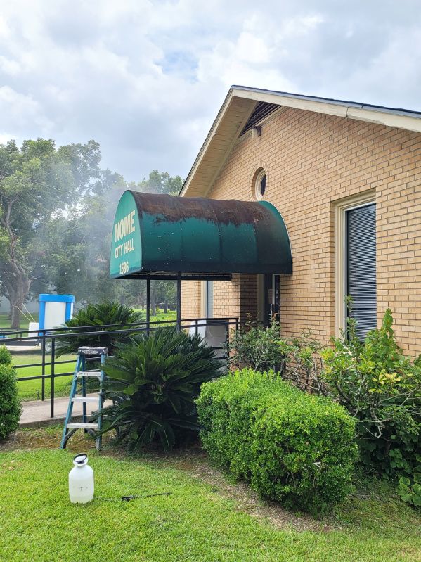 Awnings at Nome City Hall with heavy dirt and stains on the surface, showing rust marks on the green fabric. The surrounding area is tidy with a ladder and cleaning equipment in place.