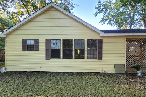 The exterior of a house with clean siding, freshly washed windows, and a refreshed look after house washing services.