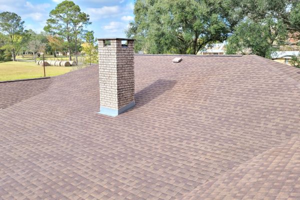 The roof of a house with clean, well-maintained shingles and a bright, refreshed appearance after roof washing services.