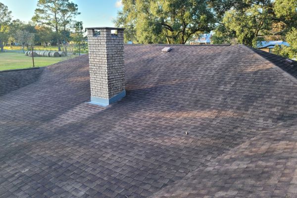 The roof of a house showing visible dirt, wear, and discoloration on the shingles, indicating the need for roof washing services.
