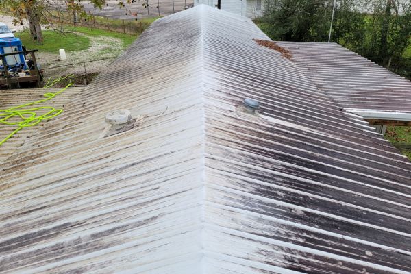 The roof of a house with visible dirt, stains, and discoloration, showing the need for roof washing services.