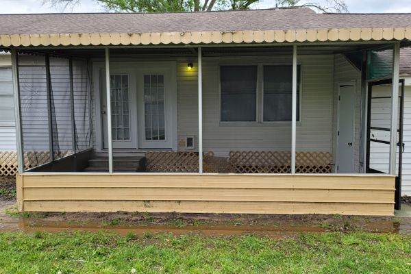 The exterior of a house with a clean porch, well-maintained siding, and a refreshed appearance after house washing services.