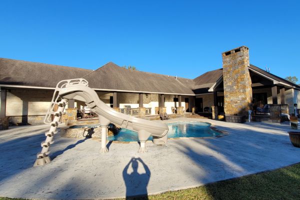 A backyard pool area with a concrete surface that appears slightly dirty and worn, with visible stains and discoloration, and the poolside not looking as clean and bright.