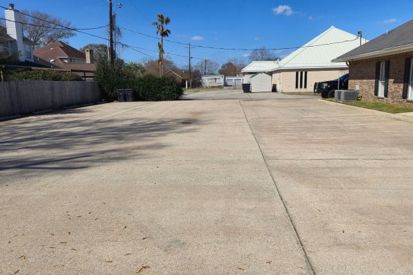 The same concrete area after a thorough cleaning, with noticeable improvements in appearance. The surface is now much cleaner, with water runoff visible from the washing process, leaving the concrete looking fresh and restored.