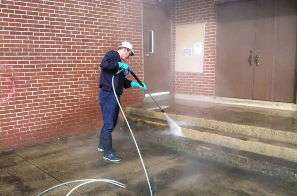 A professional cleaning technician is using a pressure washer to clean concrete steps, ensuring the surface is free of dirt, grime, and stains. This is an example of concrete washing services designed to restore and maintain the appearance of outdoor surfaces.