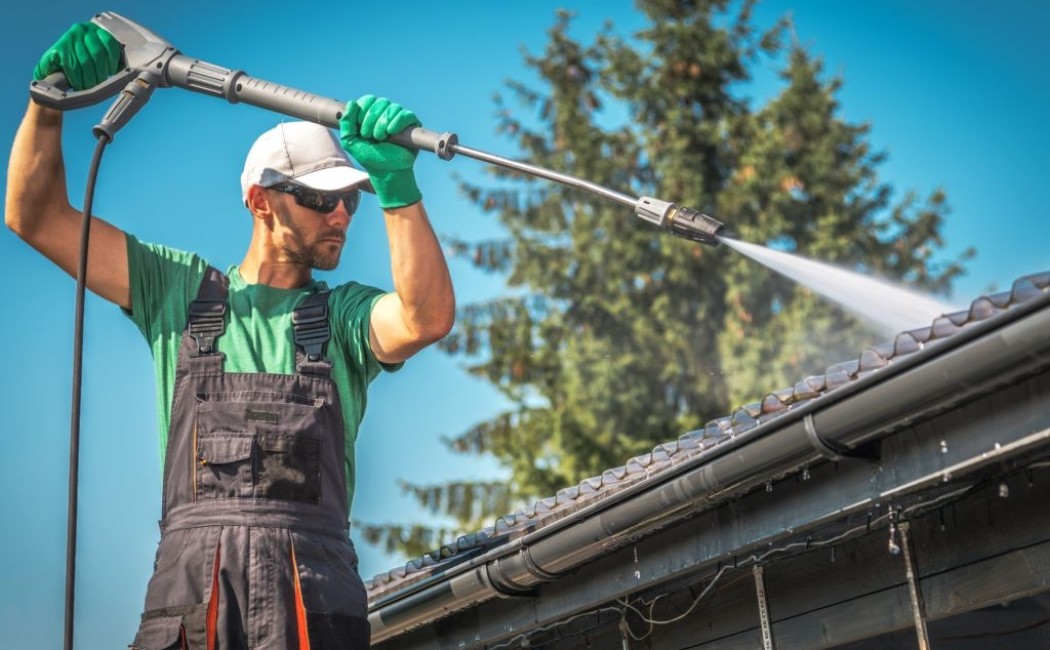 Soft washing services professional cleaning a roof with low-pressure water spray to safely remove dirt, moss, and debris without damage.